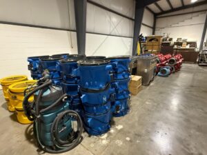 Rows of industrial air movers, HEPA vacuums, and commercial dehumidifiers inside a restoration warehouse ready for detailed mold remediation services.