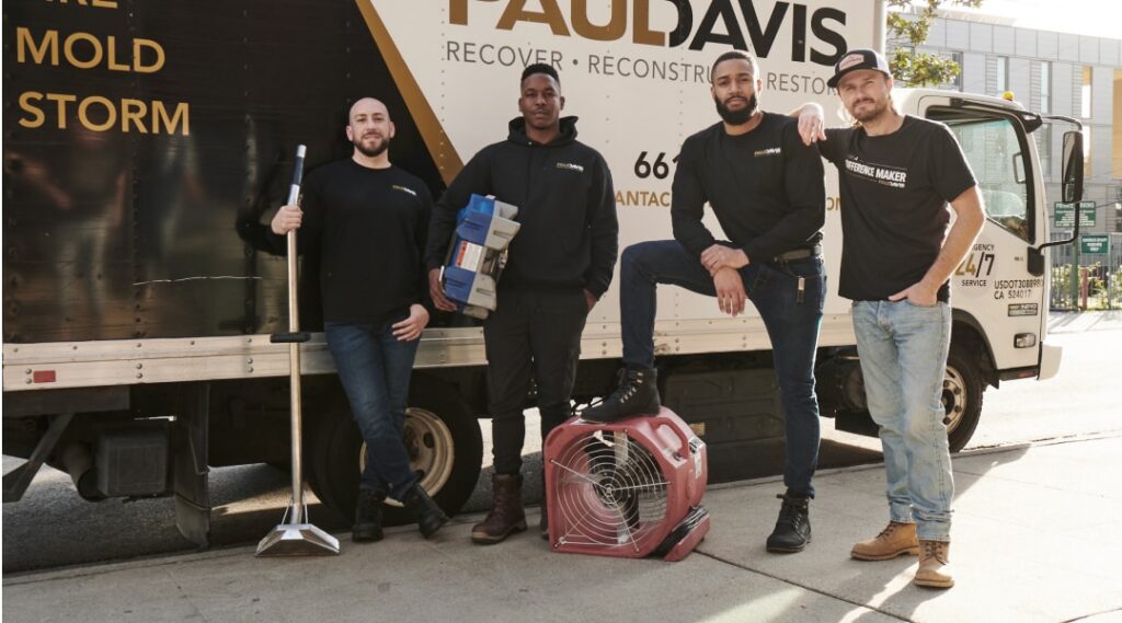 Paul Davis Restoration of Downriver Detroit, MI team standing in front of service truck with restoration equipment, ready for water, fire, mold, and storm damage response.